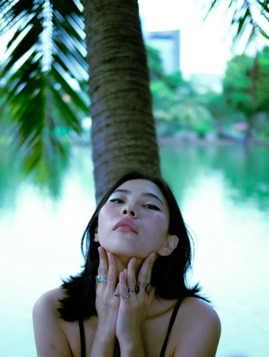 a girl posing by the water with her hands under her chin