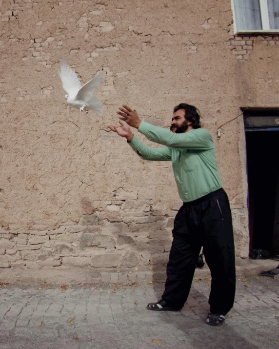 a man feeding a bird on the street