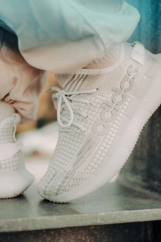 a person is tying on white shoes on top of a metal table