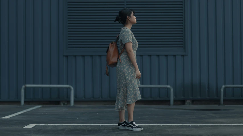 a woman in a dress stands in front of a building