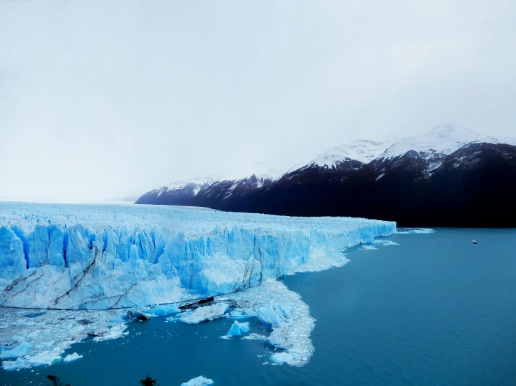 a large iceberg is surrounded by snowy mountains