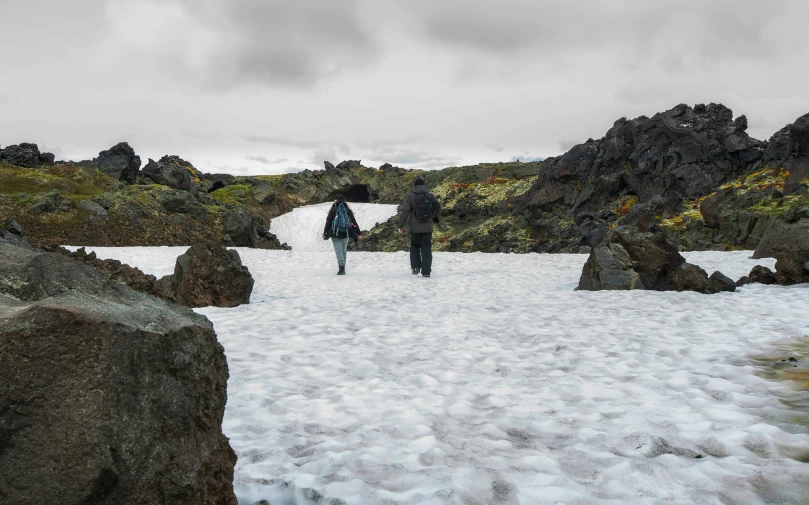 two people walk along the snowy path in the mountains