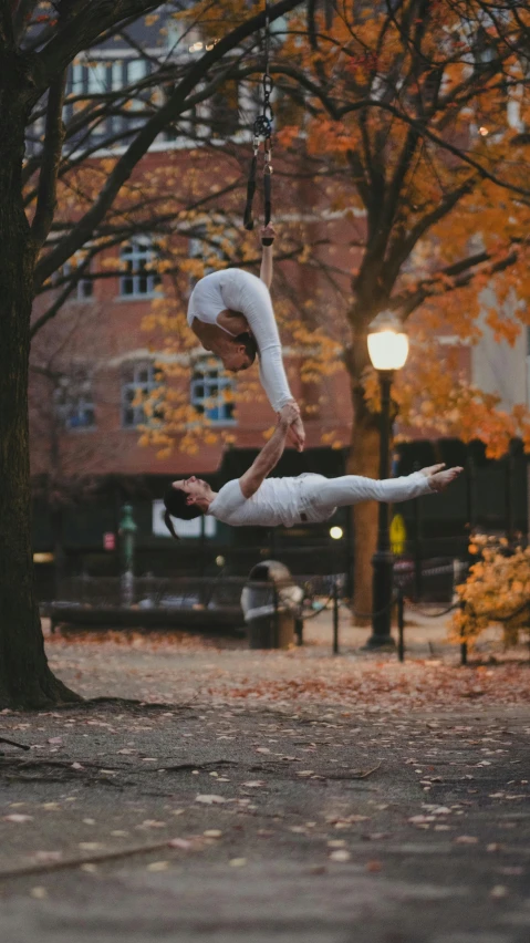 a man is doing a acrobatic move in the air by the tree