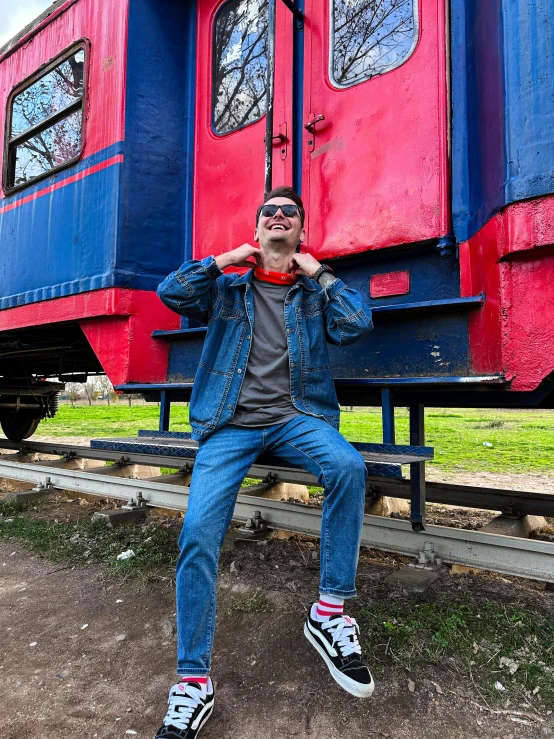 a person standing by a train with a red and blue train car