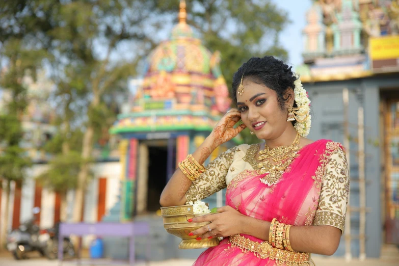 a woman wearing a gold and pink sari holding a cell phone