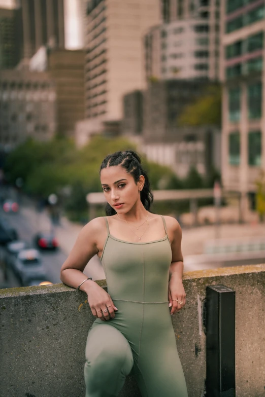 a woman posing for the camera, wearing a long green bodysuit and heels