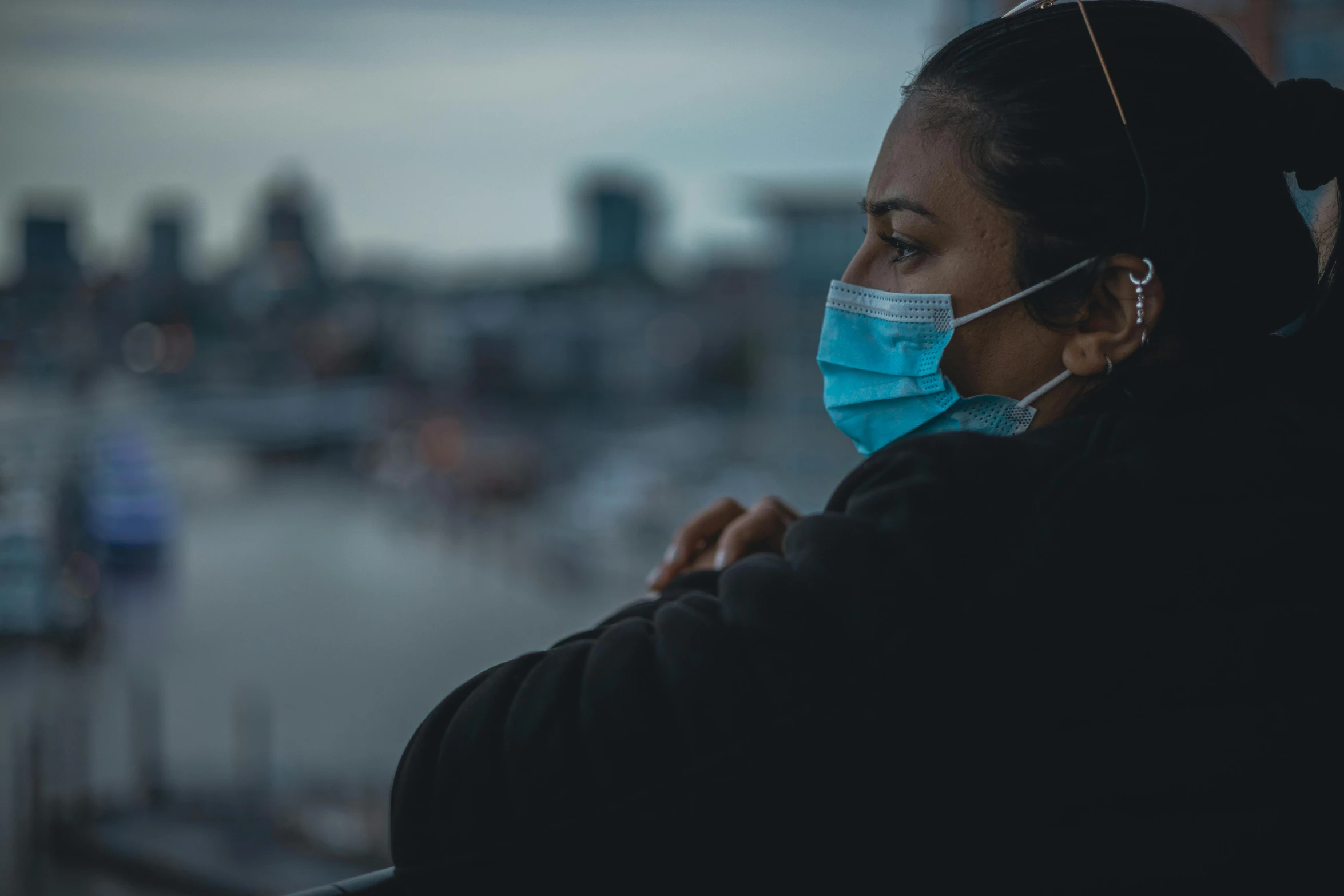 a woman wearing a surgical face mask and looking out a window