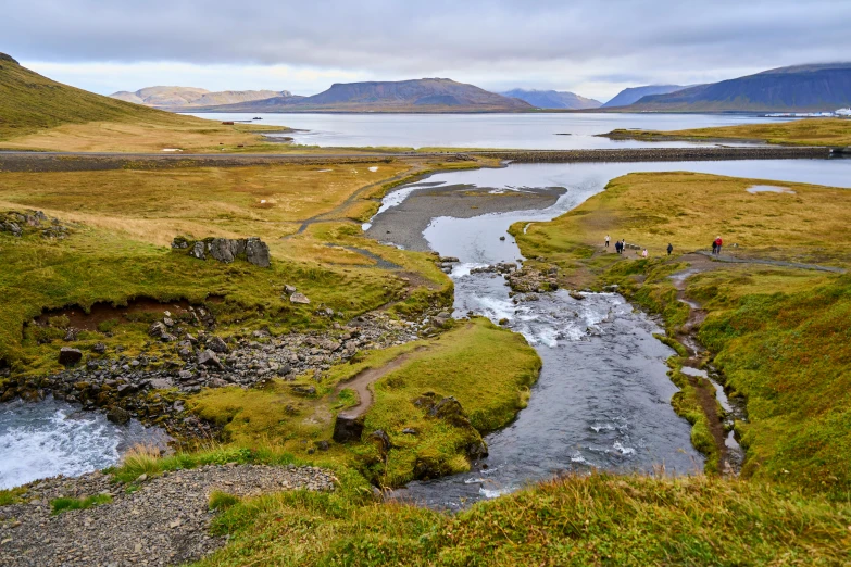 two people are standing at the edge of a small river