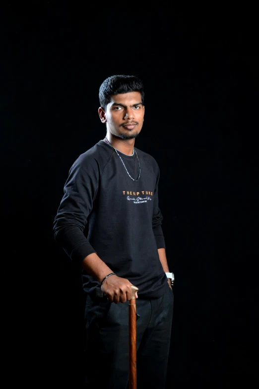 an indian man holding a cane in a black background