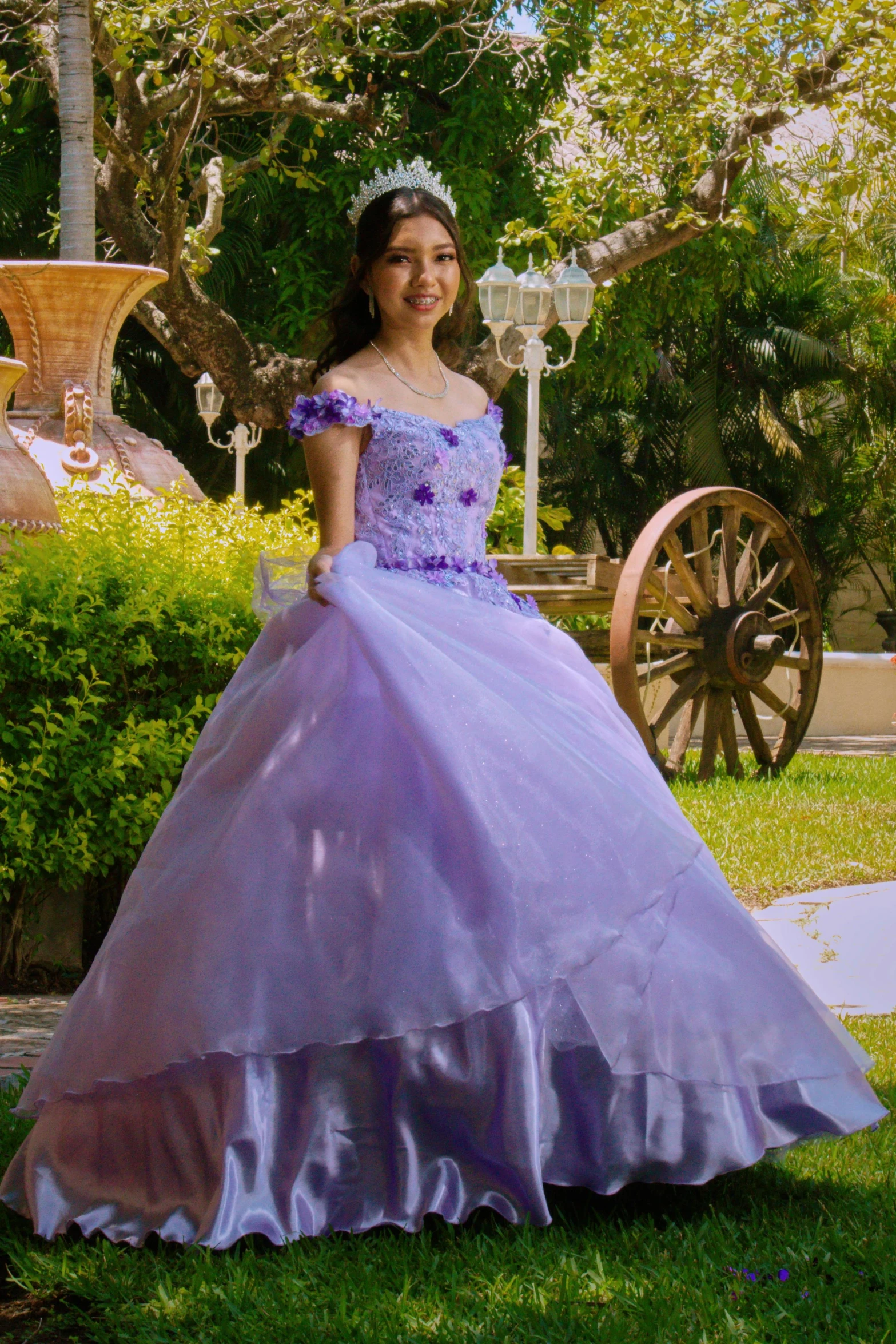 the young lady in a gown stands beside a wagon