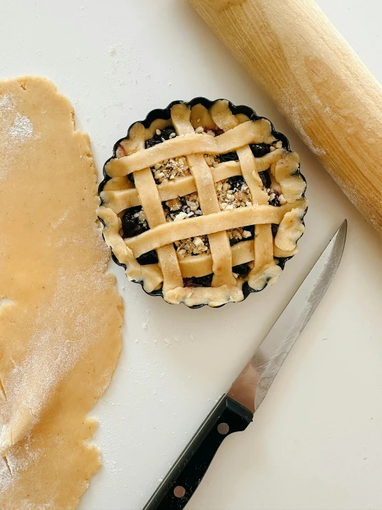 a pie crust next to a wooden spatula and rolling pin