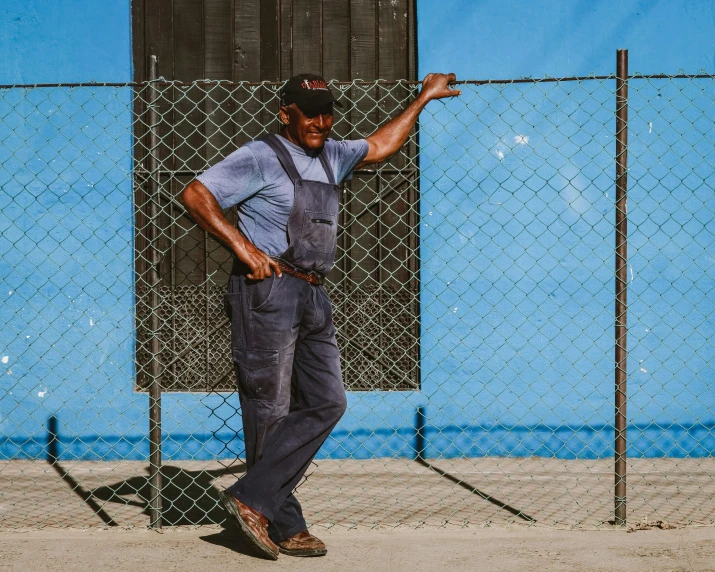 a man leaning against a chain link fence