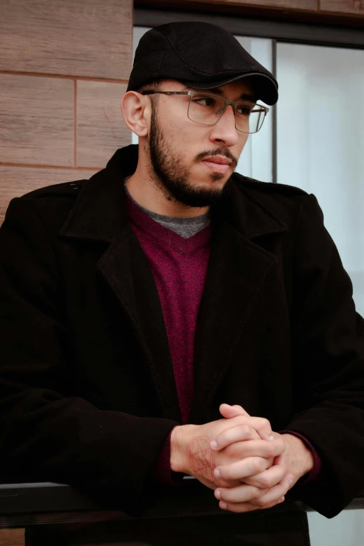 a man sitting outside while wearing a black coat