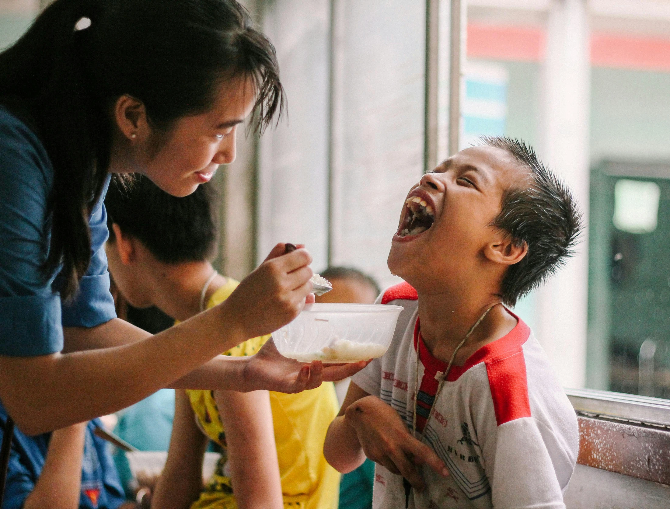 a person holding a bowl of food while standing in front of a child