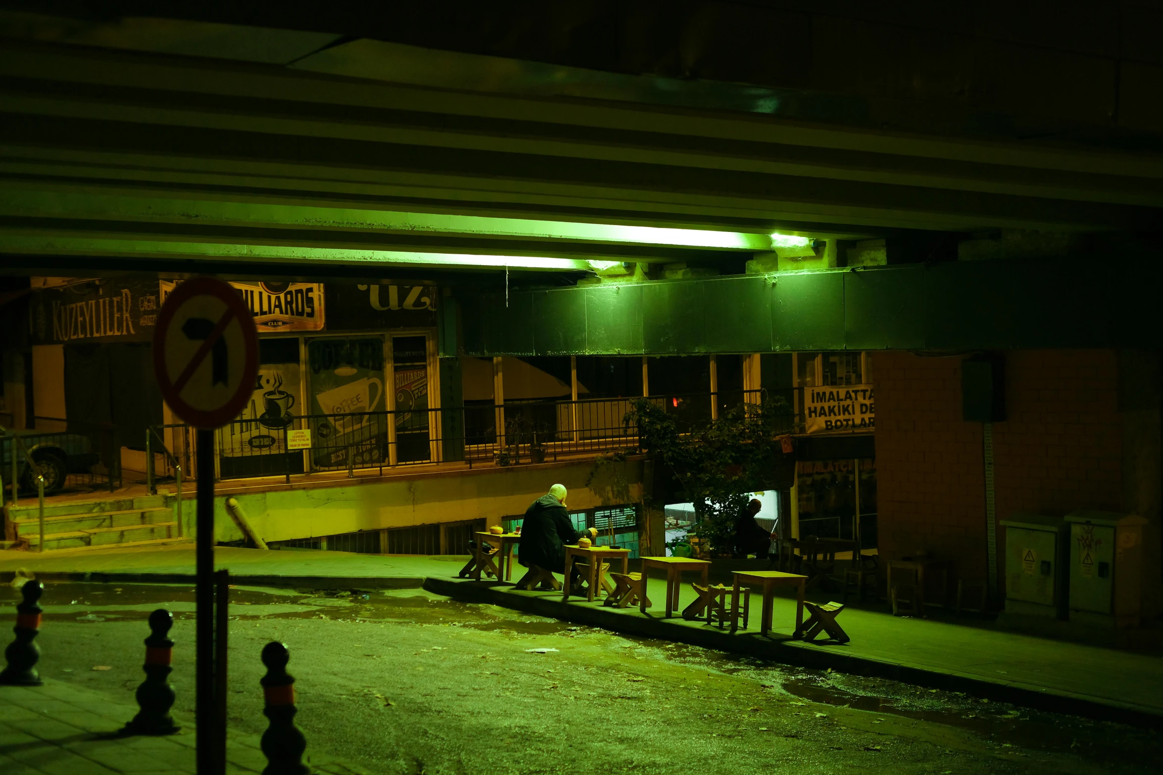 several people sitting at tables and standing on train tracks at night