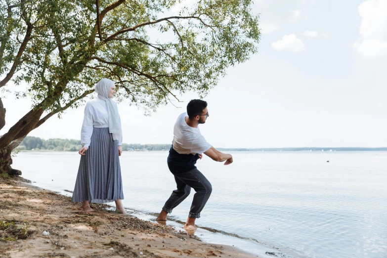 a man standing next to a woman next to the water