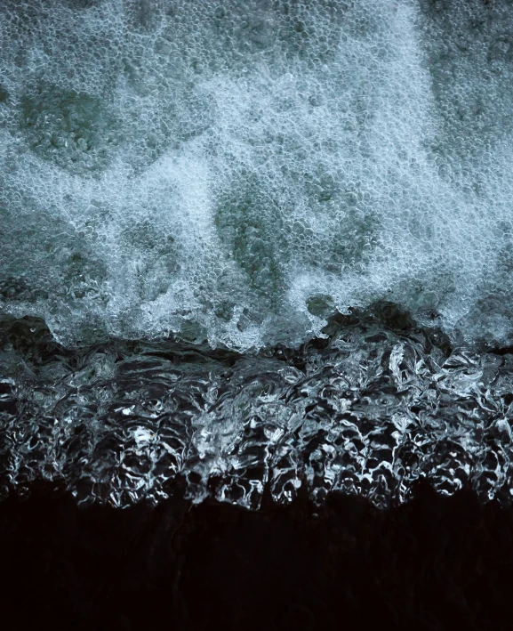 a large wave crashes upon a beach at night