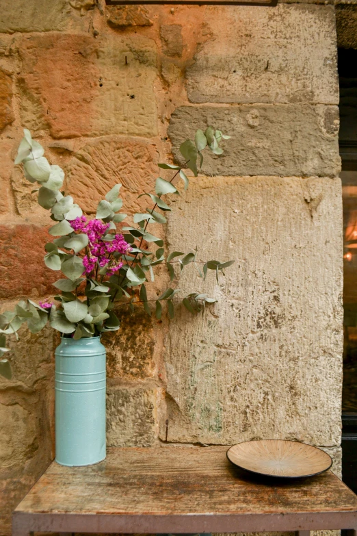 a blue mason jar holding pink flowers is shown in front of a stone wall