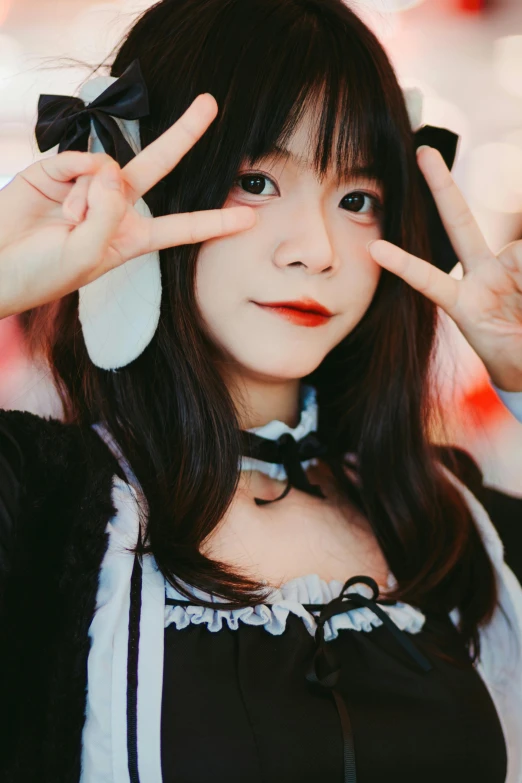 an asian woman wearing a bow holding up a peace sign