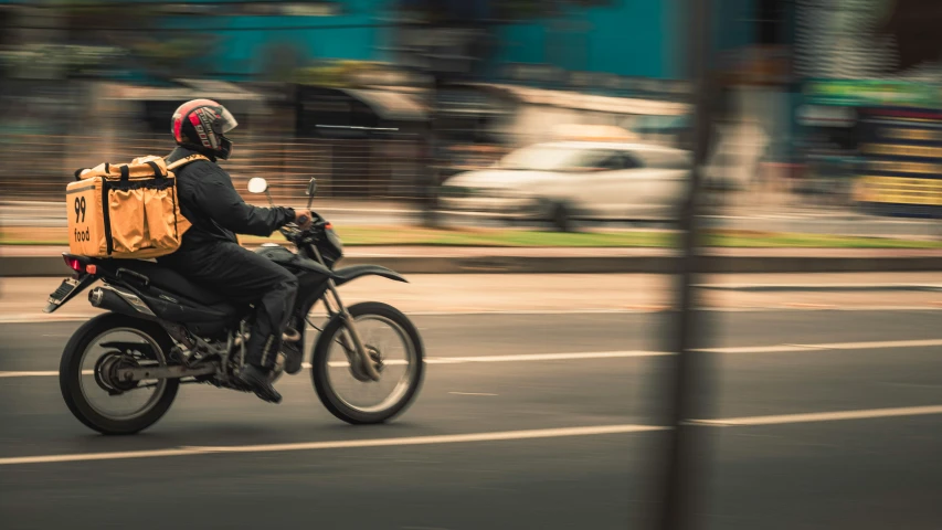 a man riding a motorcycle down the street with a backpack on back