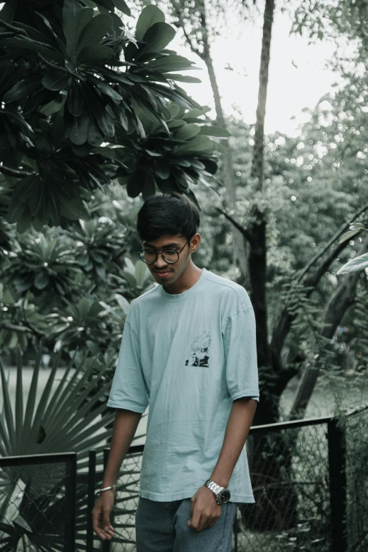 a guy in glasses is posing by a fence