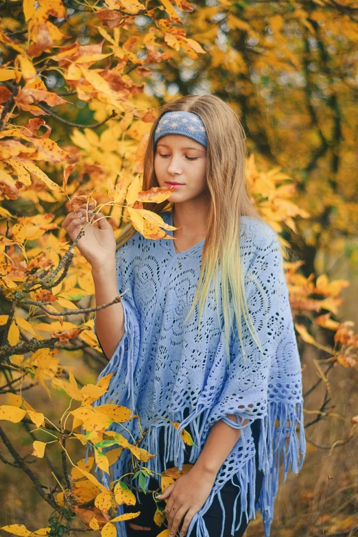 a woman wearing a head band is next to an autumn tree