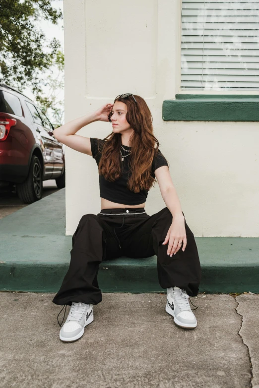 a girl in black sits on the steps next to a house