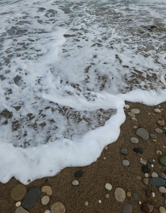 a sandy shore with waves coming in towards the shore