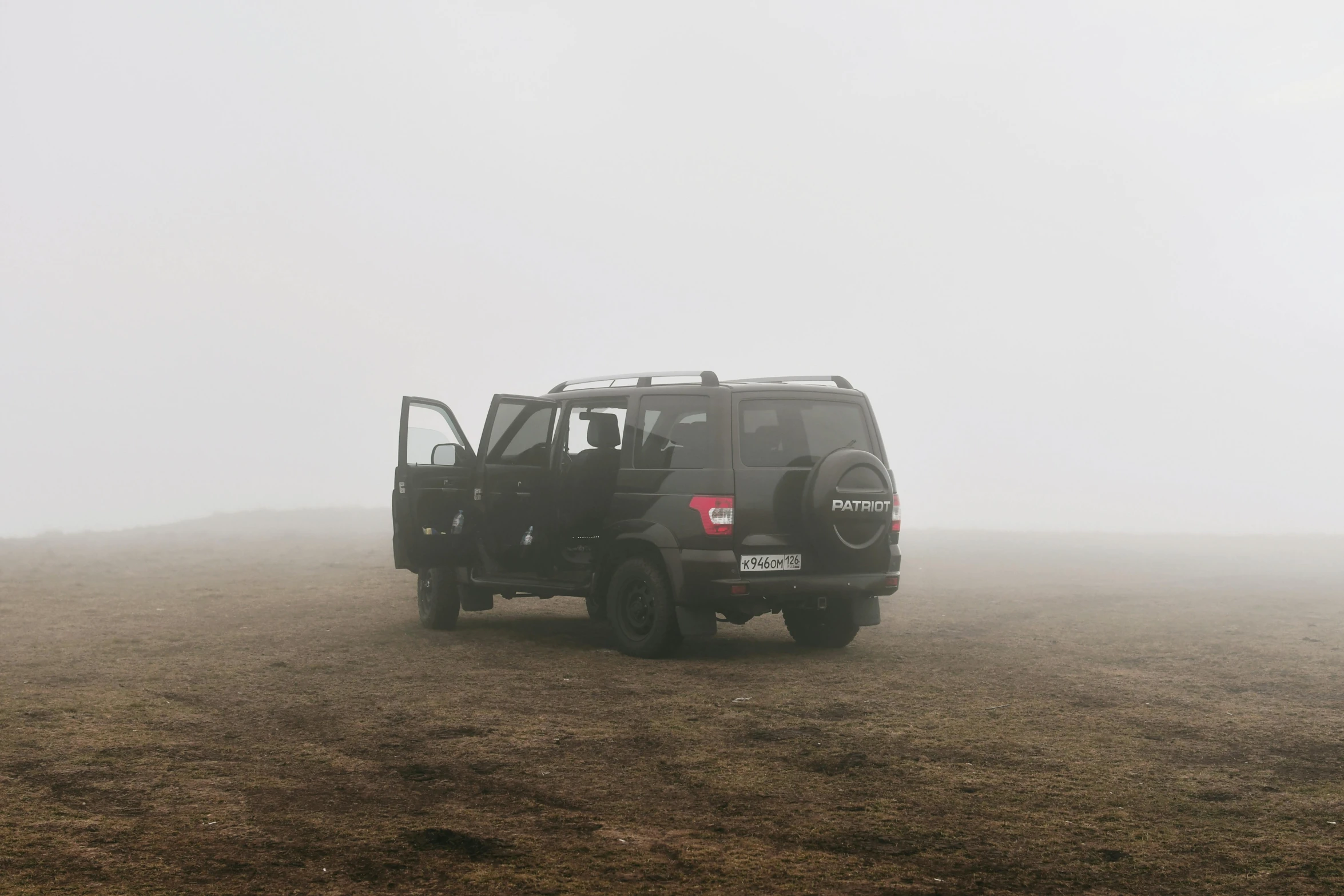 a truck traveling across a field with fog on the sky