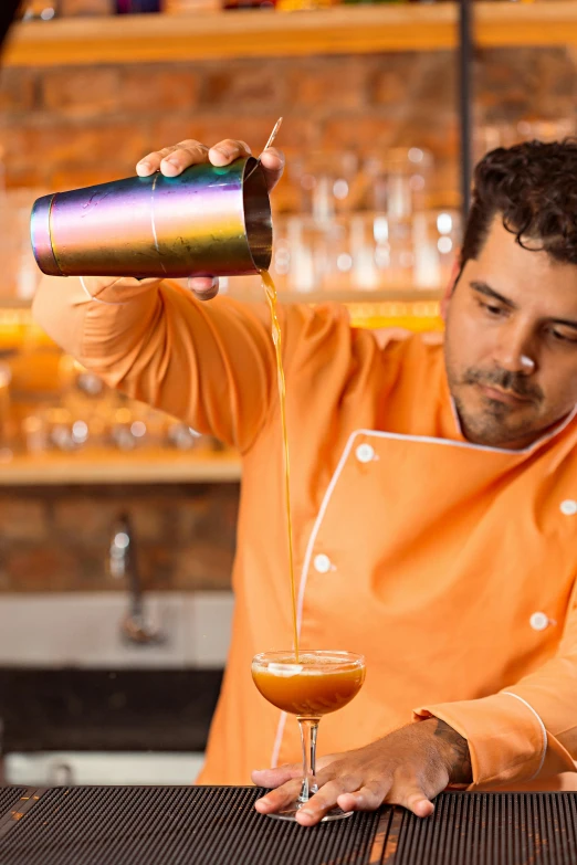 a man in an orange shirt pouring drinks into glasses