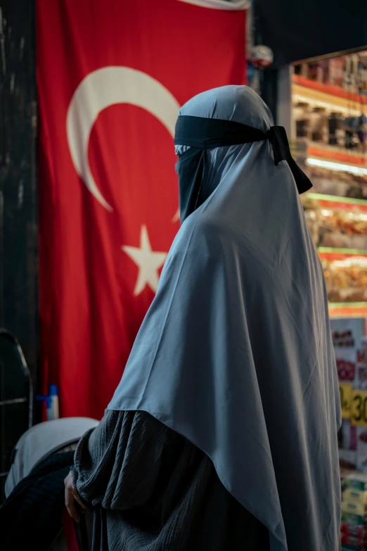 a woman with a headscarf standing next to a flag