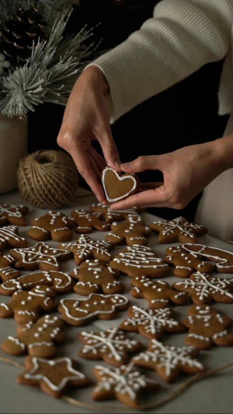 two hands  a heart shaped cookie on a table