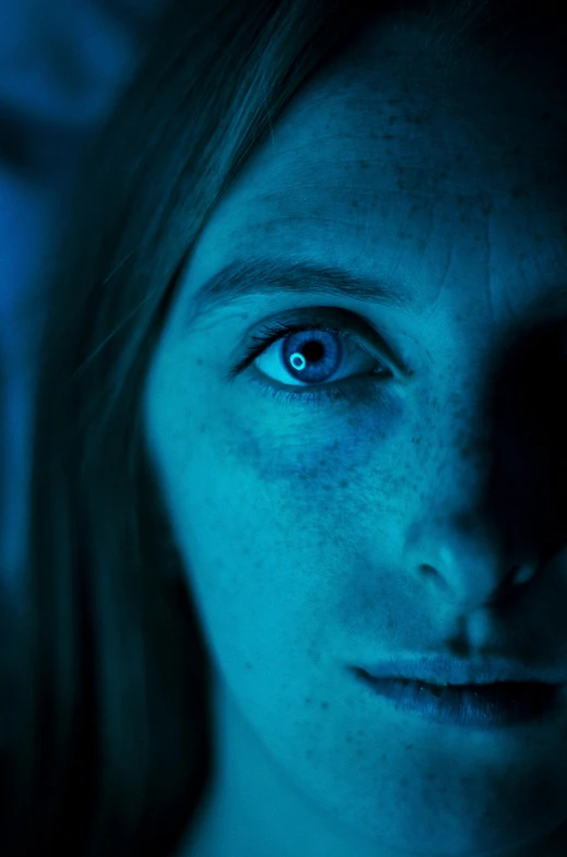 an image of woman looking at camera in a dark room