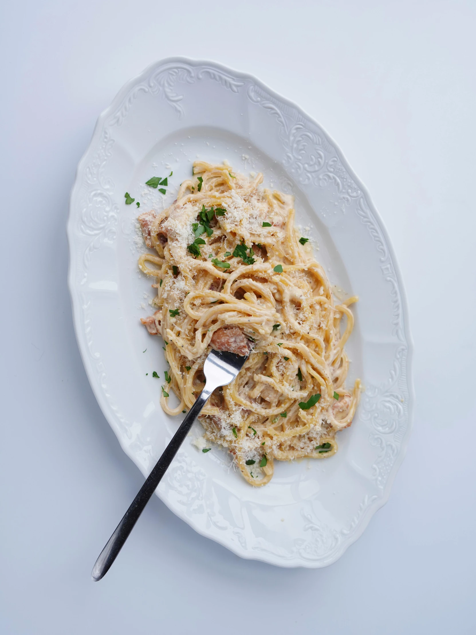 a white plate with pasta, meat and parsley