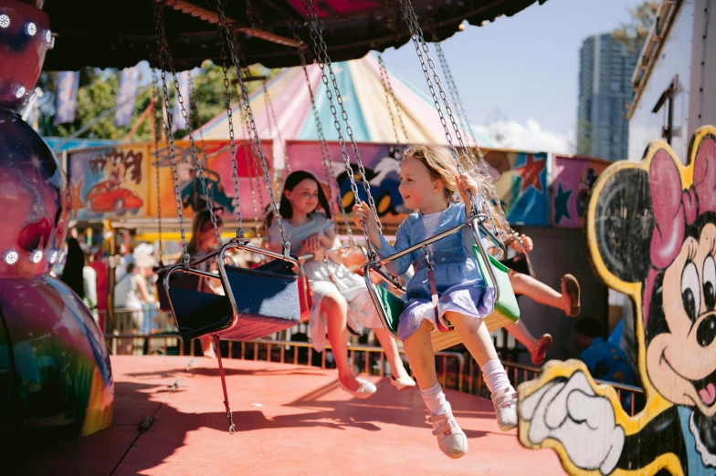 a group of girls riding in swings on a carnival