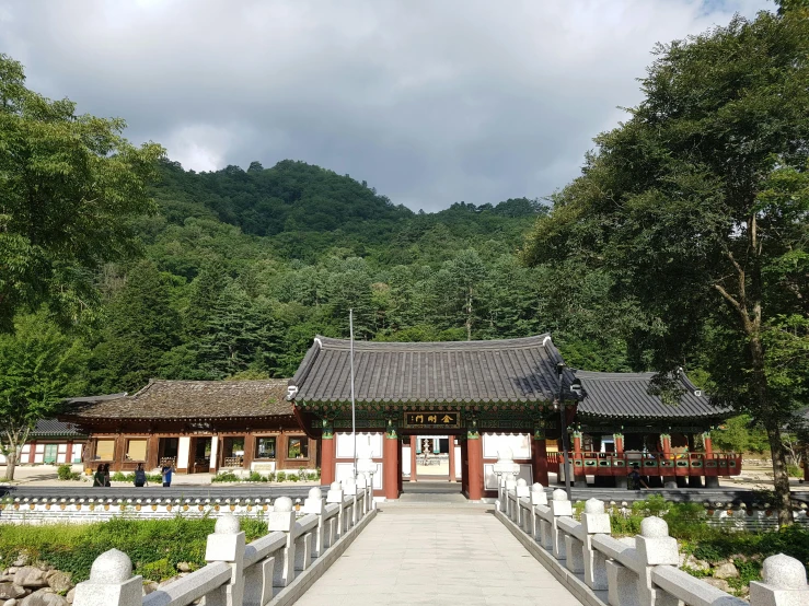 a wooden walkway leads to an asian pavilion