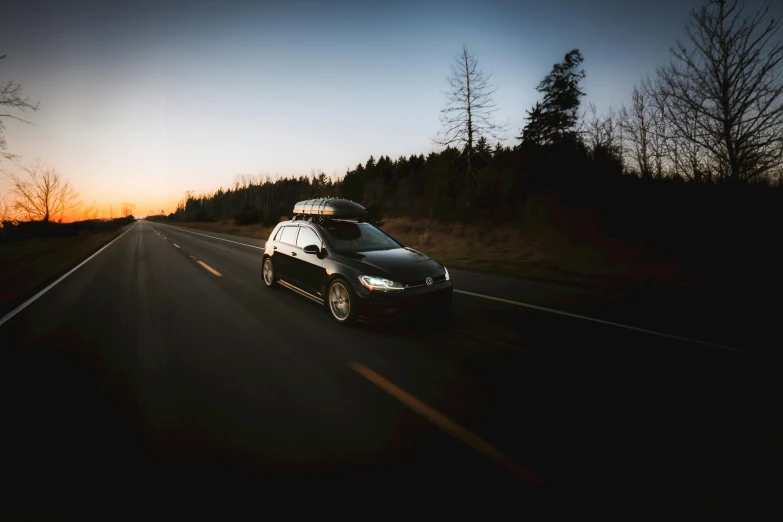 a car driving down a road at sunset