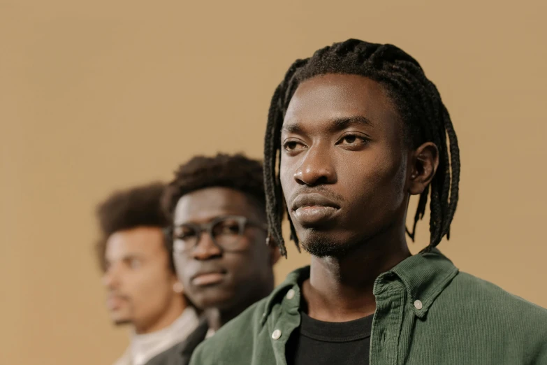 two men with dreadlocks are wearing green jackets