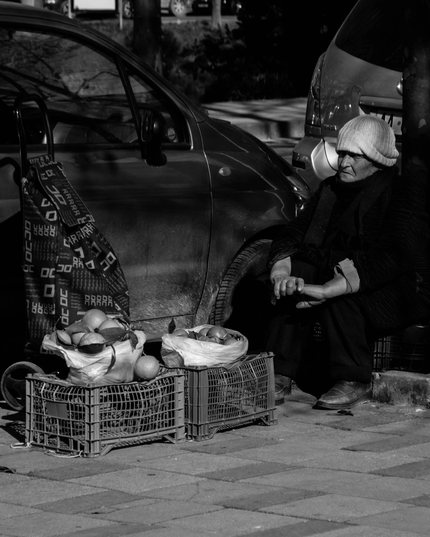 an old woman sitting by some baskets on the side walk