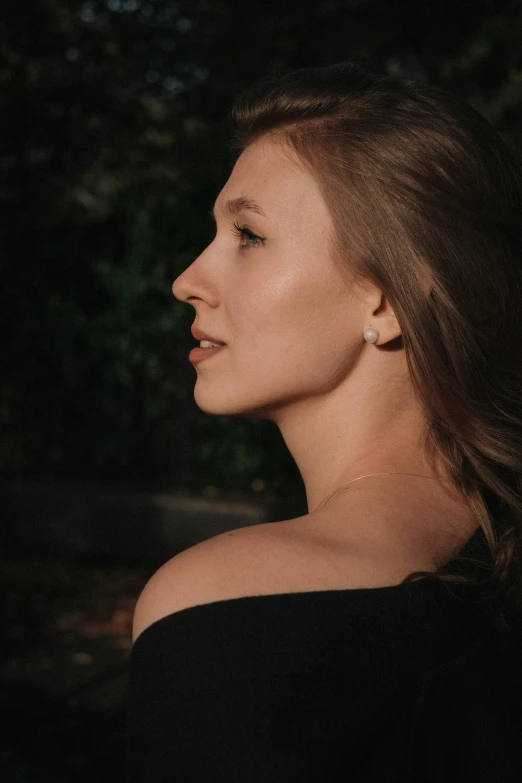 woman with long hair in the dark, wearing earrings