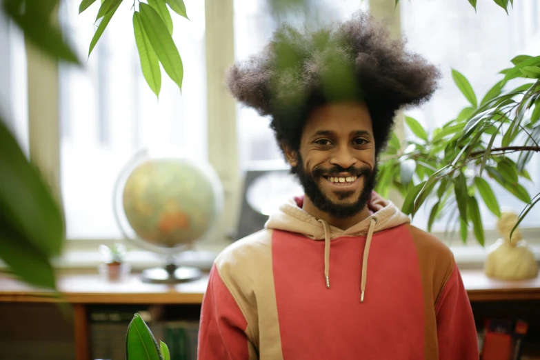 an indian man with a fake afro stands in front of a table