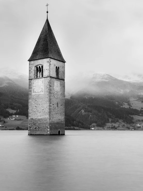 the water is full of grey fog near the steeples of a clock tower