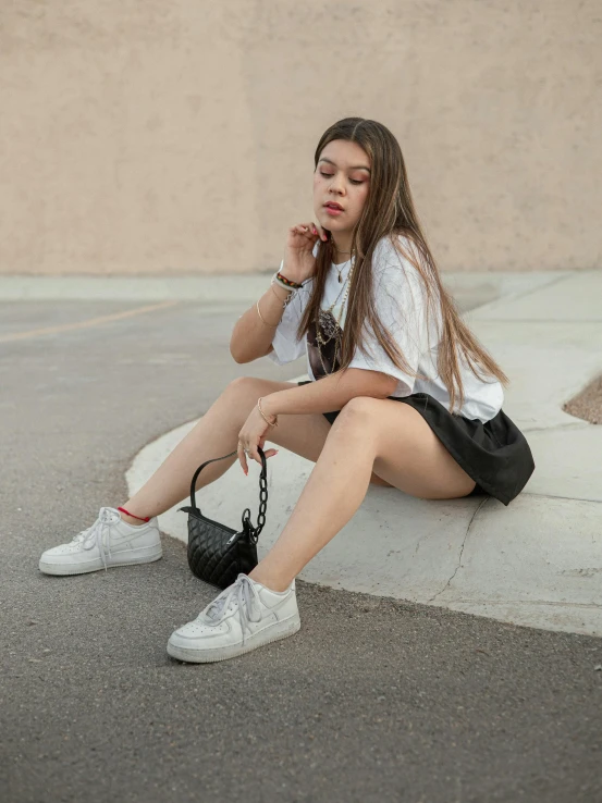 a young woman sitting on a curb with her handbag