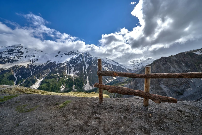 a wooden fence is shown with snowy mountains in the background