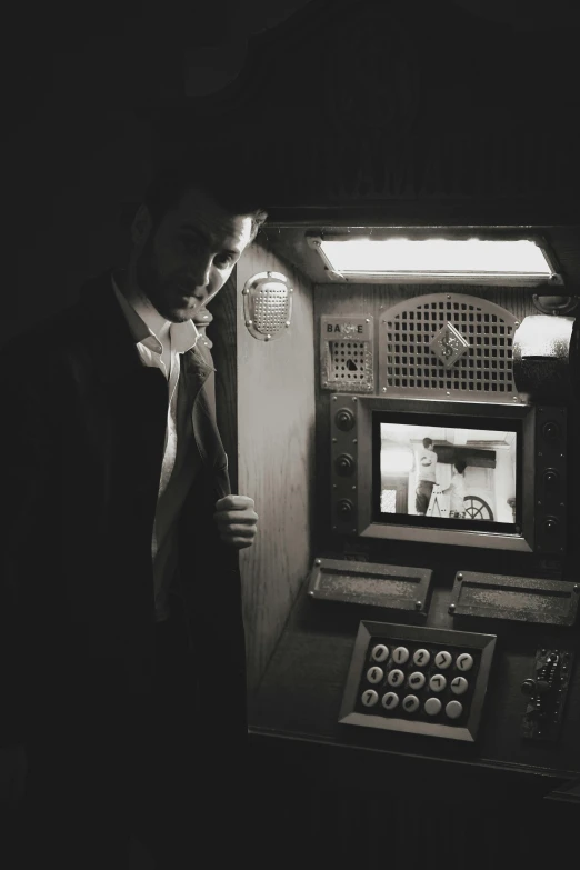 a man standing by an old typewriter in a dark room