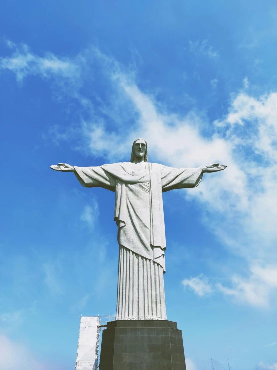 a large statue of jesus is in front of a blue sky