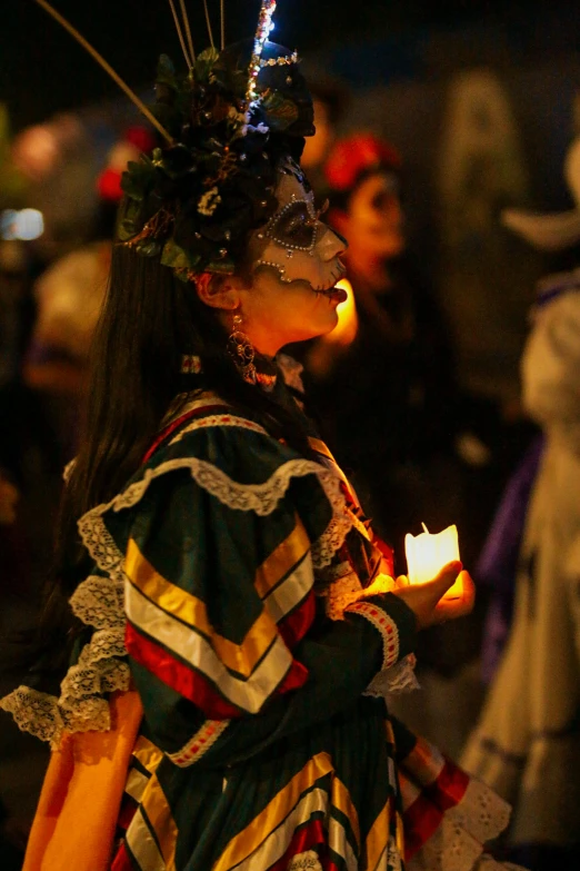 the woman is dressed in costume and holding a candle