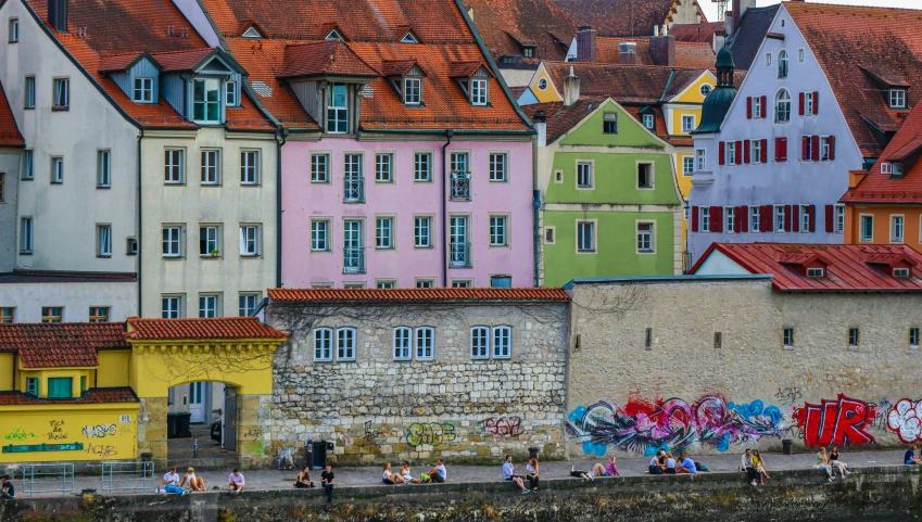a group of people walking by a wall and some houses