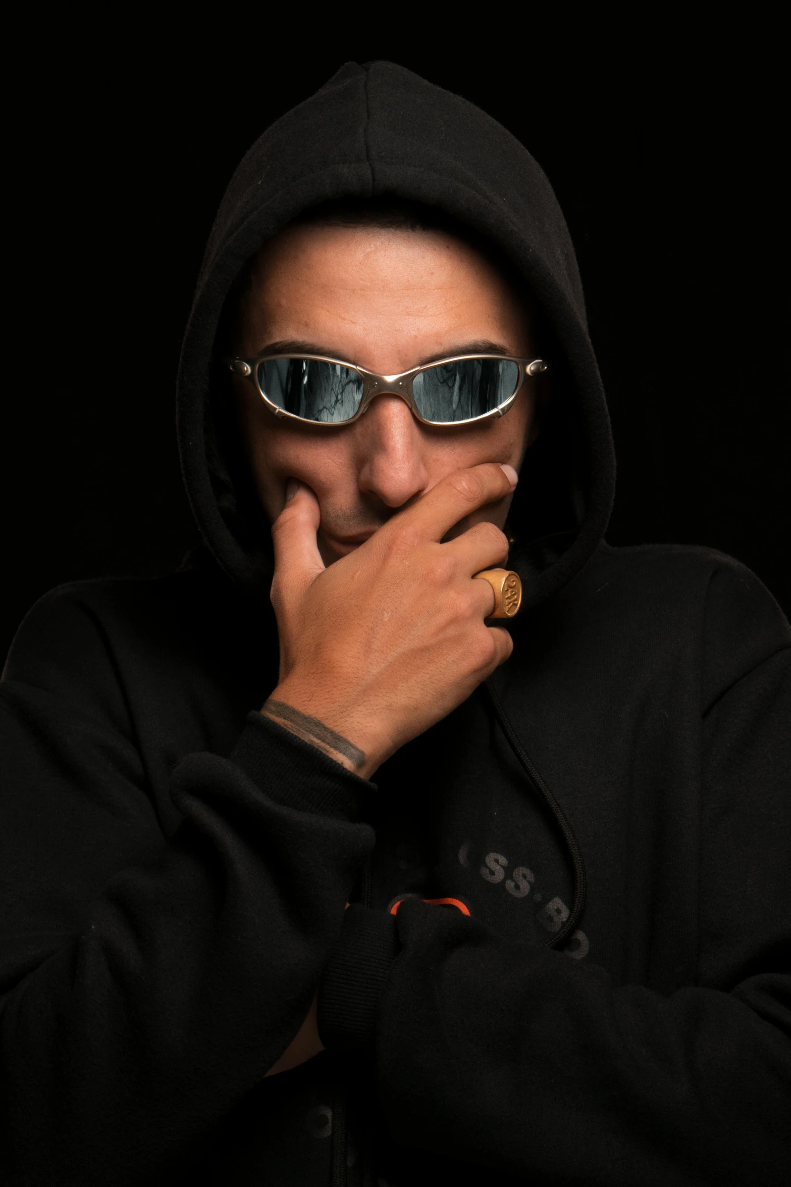 a man wearing sunglasses covers his mouth as he puts his hand on his face