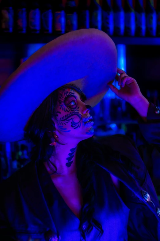 a woman wearing face paint and a sombrero on her head